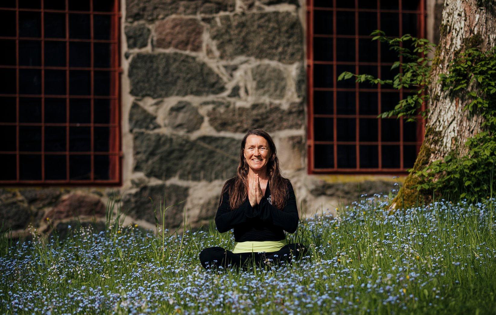 Bild p&aring; Maria St&aring;hl sittandes i meditationsst&auml;llning bland bl&aring; blommor
